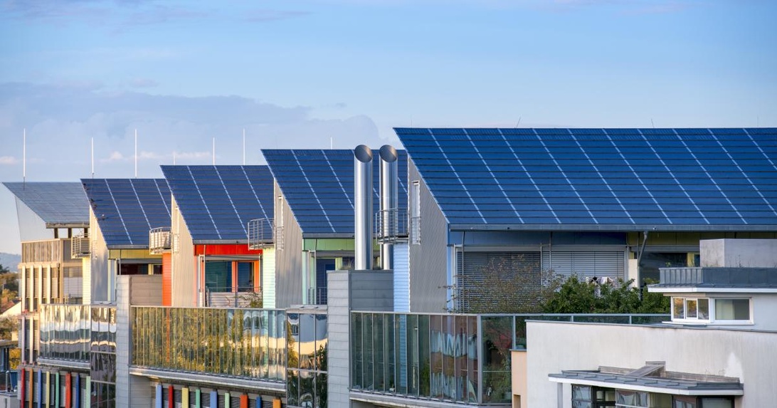 Nahaufnahme der berühmten Solarsiedlung in Freiburg mit modernen Wohnhäusern und großflächigen Solaranlagen auf den Dächern. Die farbenfrohen, energieeffizienten Gebäude mit blauen Photovoltaik-Modulen sind ein international anerkanntes Beispiel für nachhaltige Stadtplanung.