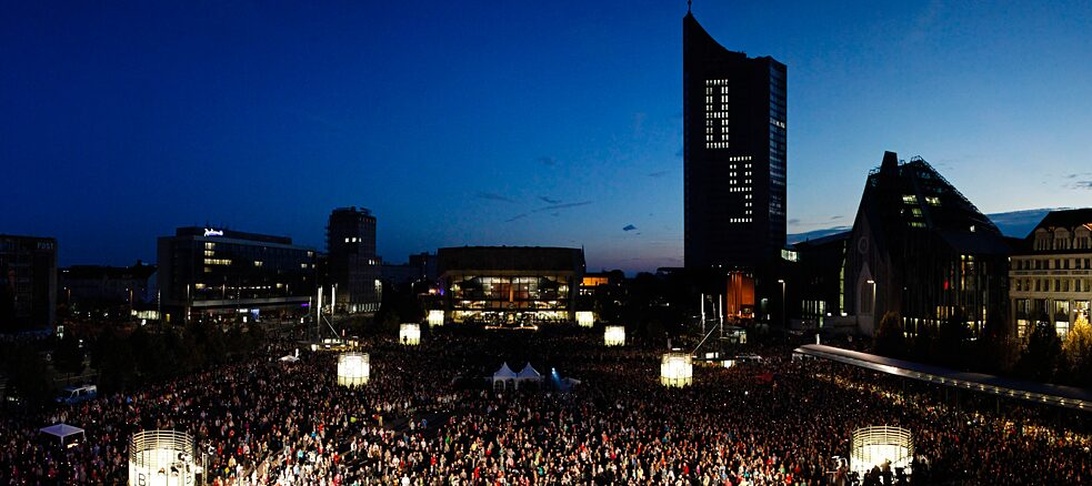 Nächtliches Panorama des Leipziger Augustusplatzes während einer Großveranstaltung mit beleuchteten Wahrzeichen wie dem City-Hochhaus.